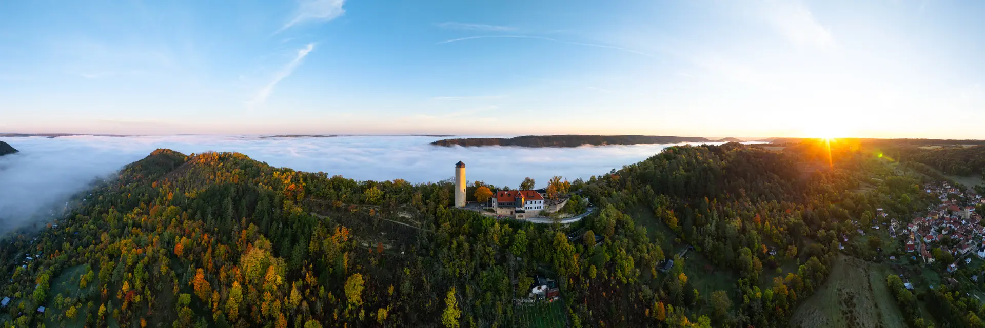 Der Fuchsturm auf dem Hausberg bei Jena ragt bei Sonnenaufgang aus einem Nebelmeer