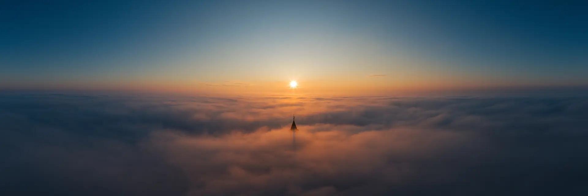 Turmspitze der Leuchtenburg ragt bei Sonnenaufgang aus einem geschlossenen Nebelmeer